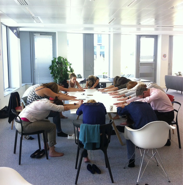 Groupe de personne faisant du yoga autour d'une table pendant la semaine de qualité de vie au travail